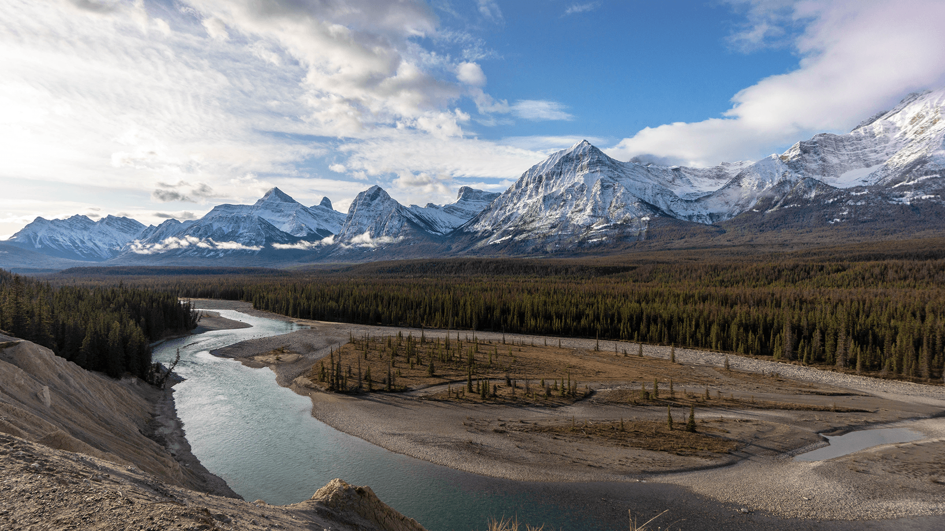 Distant mountain range in the background, vast open field in the foreground surrounded by a moving lake